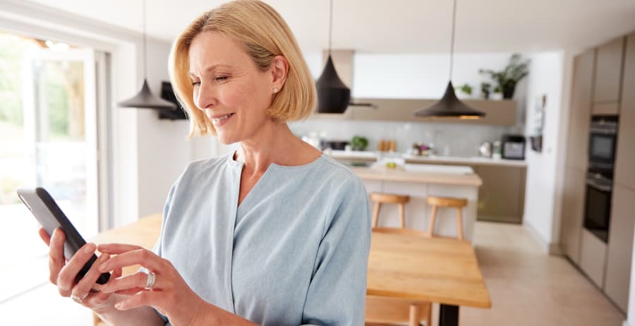Homeowner holding a smartphone in a room filled with sunlight